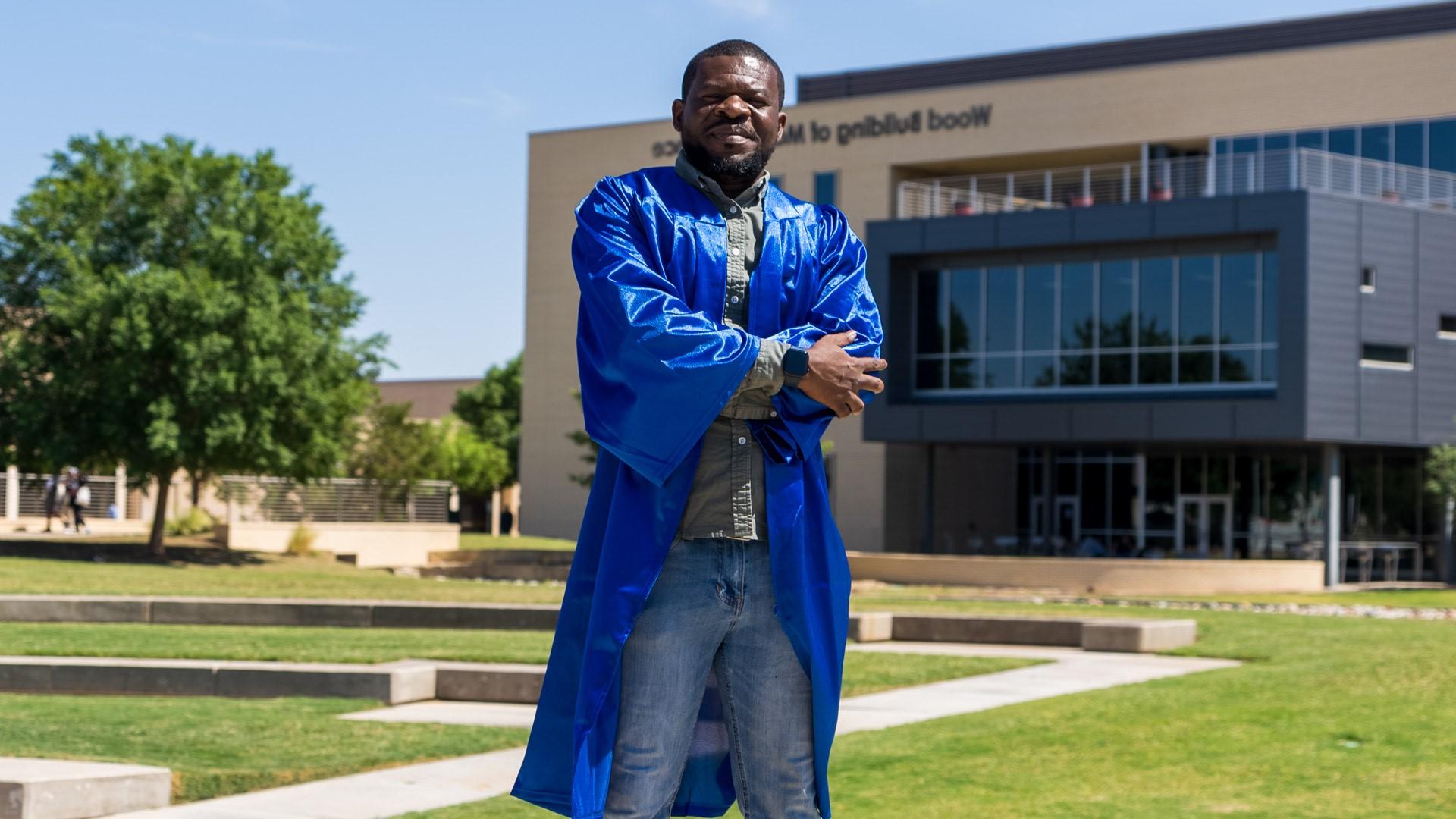 Man with arms crossed in graduation gown